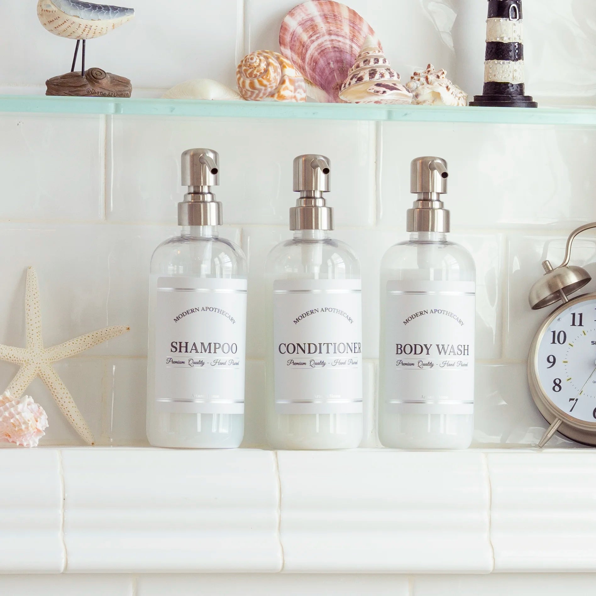 Beautiful set of three soap dispensers for showers in a bathroom niche with coordinated labels reading "Shampoo", "Conditioner", and "Body Wash"