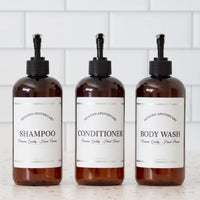 Amber PET set of refillable bottles with black pumps and coordinated labels for the shower.