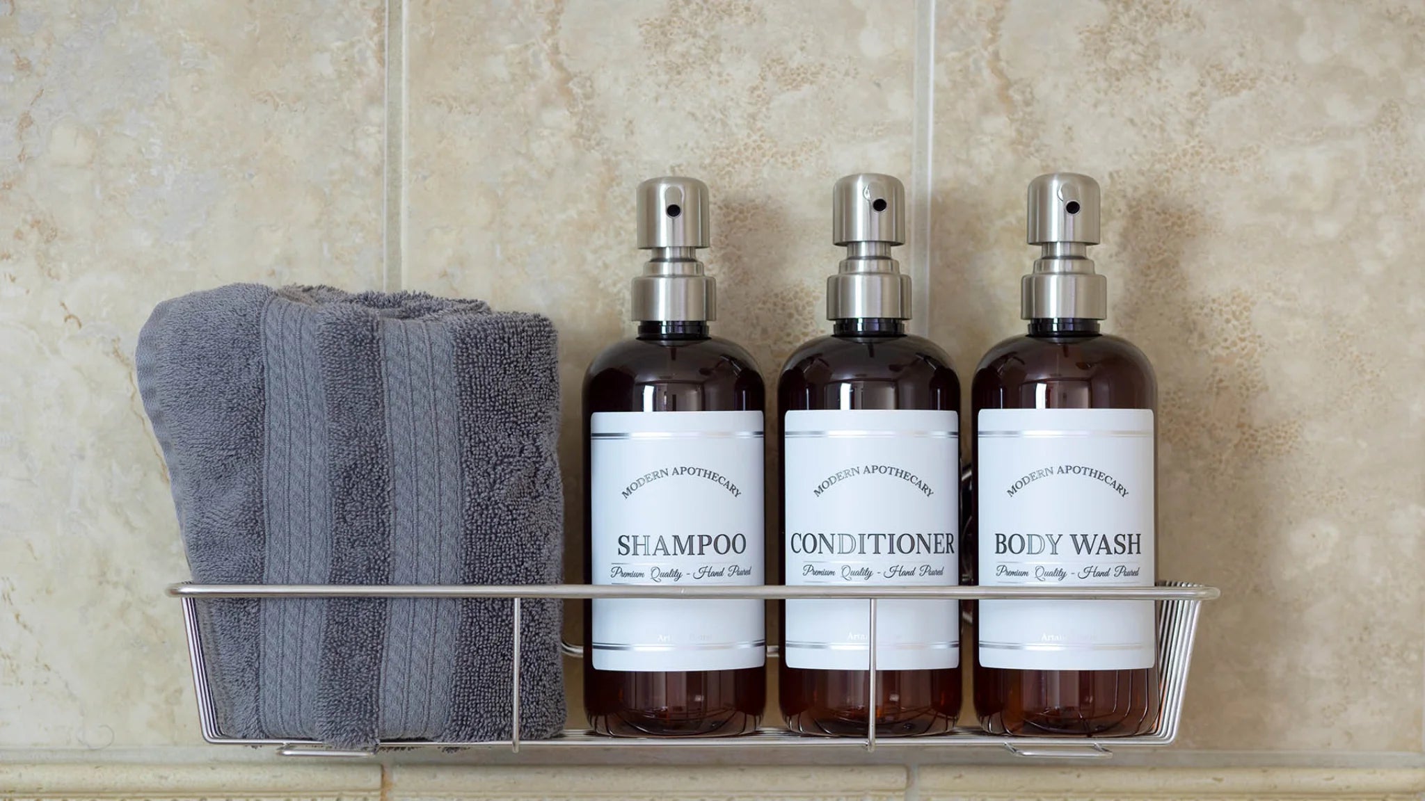 Shower shelf with gray wash cloth, 3 amber bottles with pumps and clean labels. bathroom goals, beautiful refillable bottles for the shower in amber with stainless steel pumps