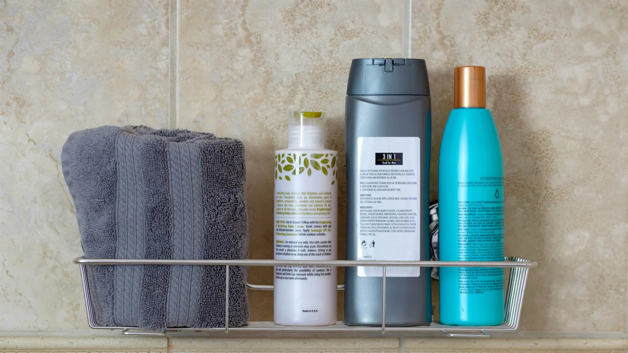 Shower rack with gray towel, ugly shampoo, conditioner & body wash bottles. how to declutter shower replace mismatched ugly shampoo bottles